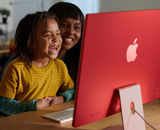 Une famille en train de rire en regardant une émission sur un iMac.