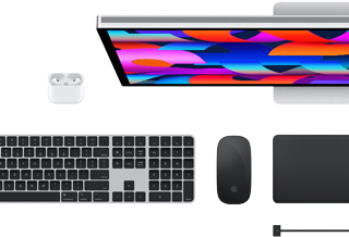 Accessoires Mac vus d’en haut : Studio Display, AirPods, Magic Keyboard, Magic Mouse et Magic Trackpad